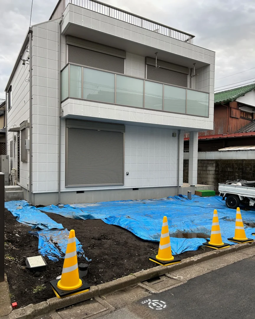 外構着工前の様子。ブルーシートやカラーコーンが設置された、土が剥き出し状態の新築二世帯住宅の前面スペース。