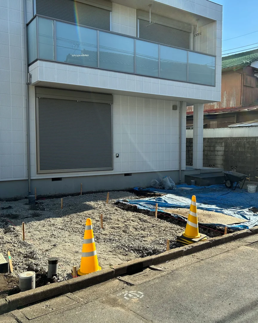 外構施工中の様子。駐車スペースとなる前面道路沿いの敷地に、砕石が均一に敷き詰められ木杭が立てられた状態。